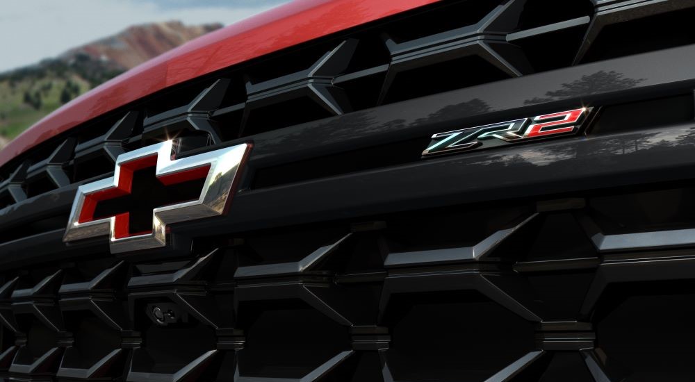 A close-up on the grille of a red 2024 Chevy Silverado 2500 HD ZR2 is shown.