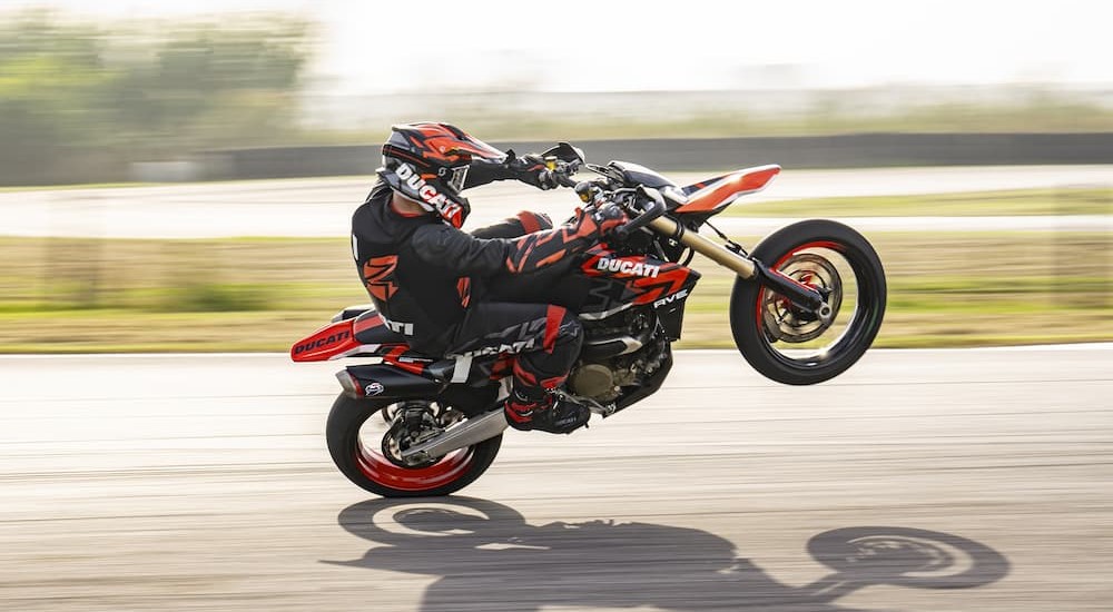 A person is shown riding a black and red 2024 Ducati Hypermotard 698 Mono on a track.