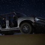 A gray 2024 Ford Bronco is shown parked under the stars at night.
