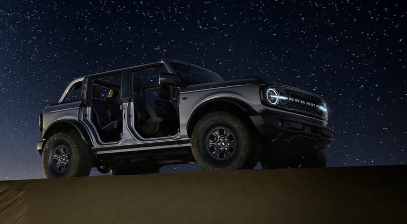 A gray 2024 Ford Bronco is shown parked under the stars at night.