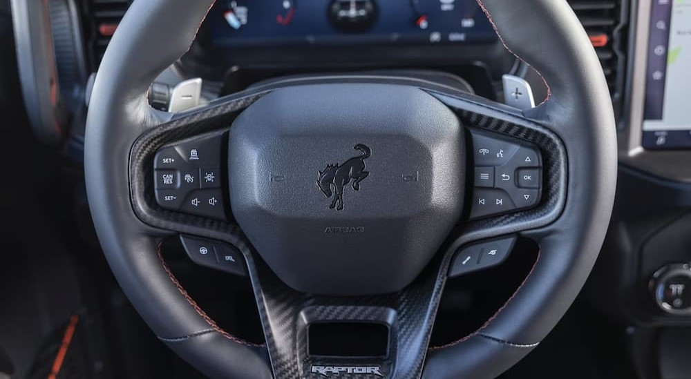 A close-up of a black steering wheel in a 2024 Ford Bronco Raptor is shown.