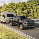 A black 2024 Ford F-150 Platinum is shown towing a trailer.