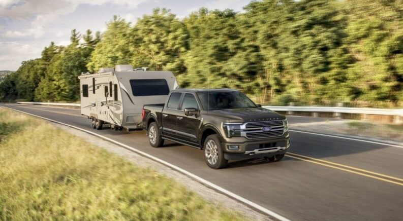 A black 2024 Ford F-150 Platinum is shown towing a trailer.