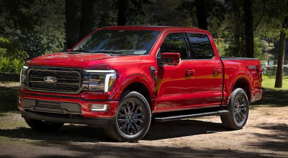 A red 2024 Ford F-150 is shown parked near a pond.
