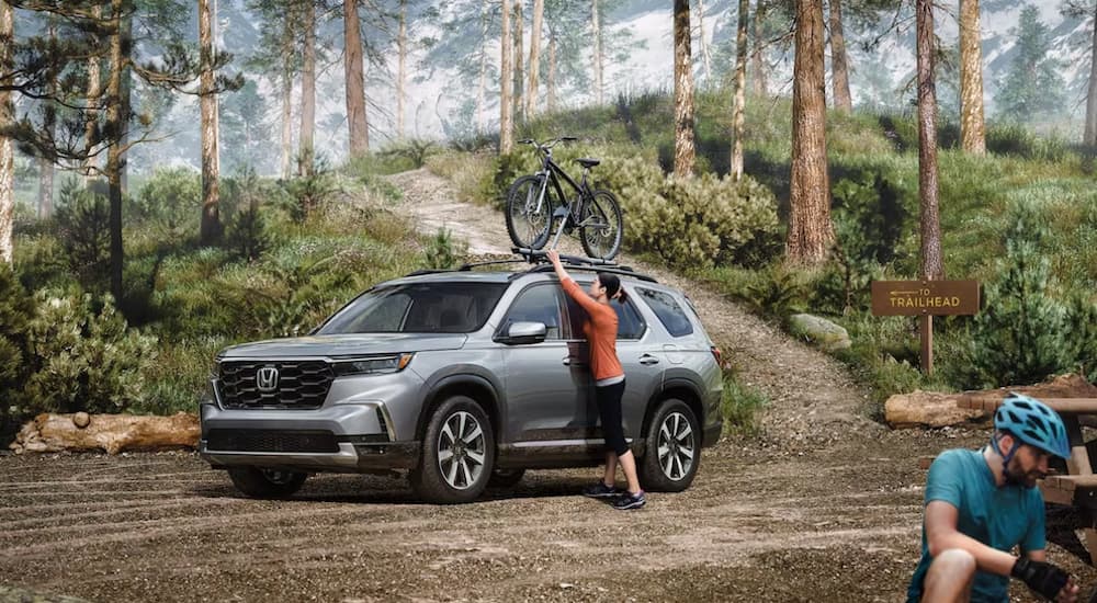 A grey 2024 Honda Pilot is shown parked off-road.