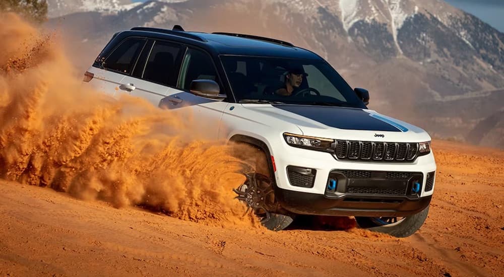 A white 2024 Jeep Grand Cherokee 4xe is shown driving off-road.