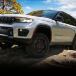 A white 2024 Jeep Grand Cherokee 4xe is shown parked off-road.