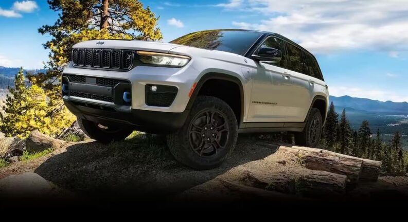A white 2024 Jeep Grand Cherokee 4xe is shown parked off-road.