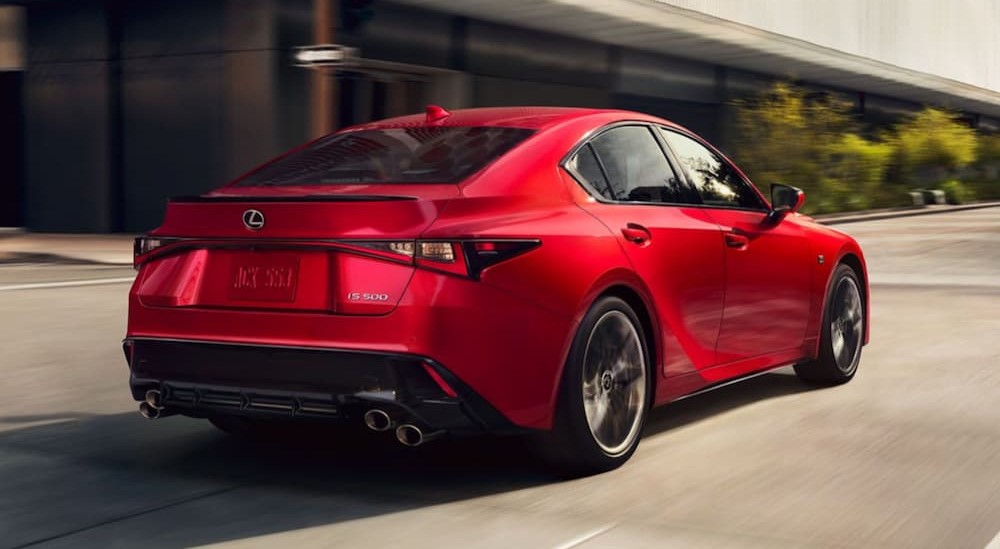 A red 2024 Lexus IS 500 F Sport is shown driving on a city street.