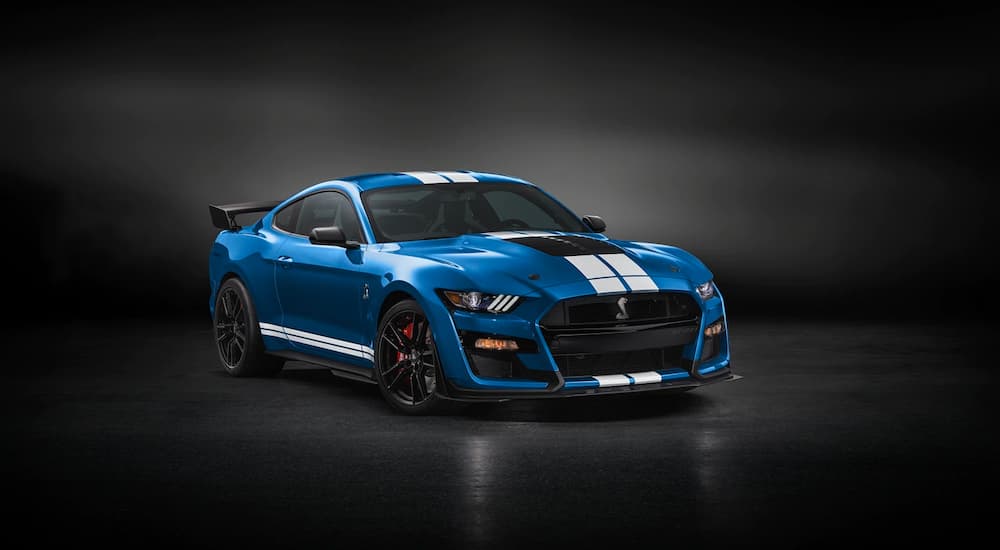 A blue and white 2022 Ford Mustang Shelby GT500 is shown parked in a dark room.