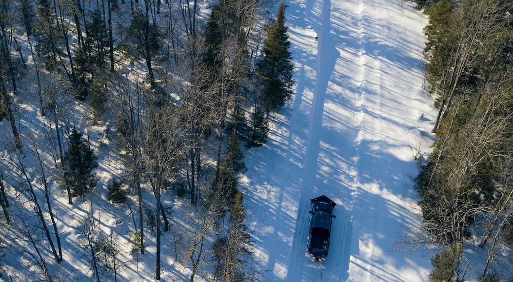 A black 2023 Chevy Silverado 1500 HD is shown from above, plowing a snowy road.