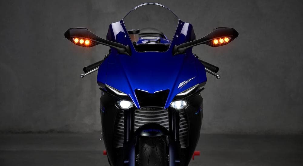 A blue 2023 Yamaha YZF-R1 is shown parked in a garage.