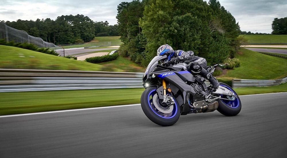 A biker is shown riding a blue 2023 Yamaha YZF-R1M down a track.