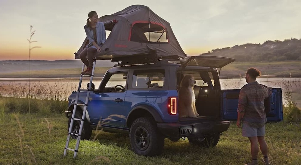 A blue 2024 Ford Bronco is shown parked near a lake.