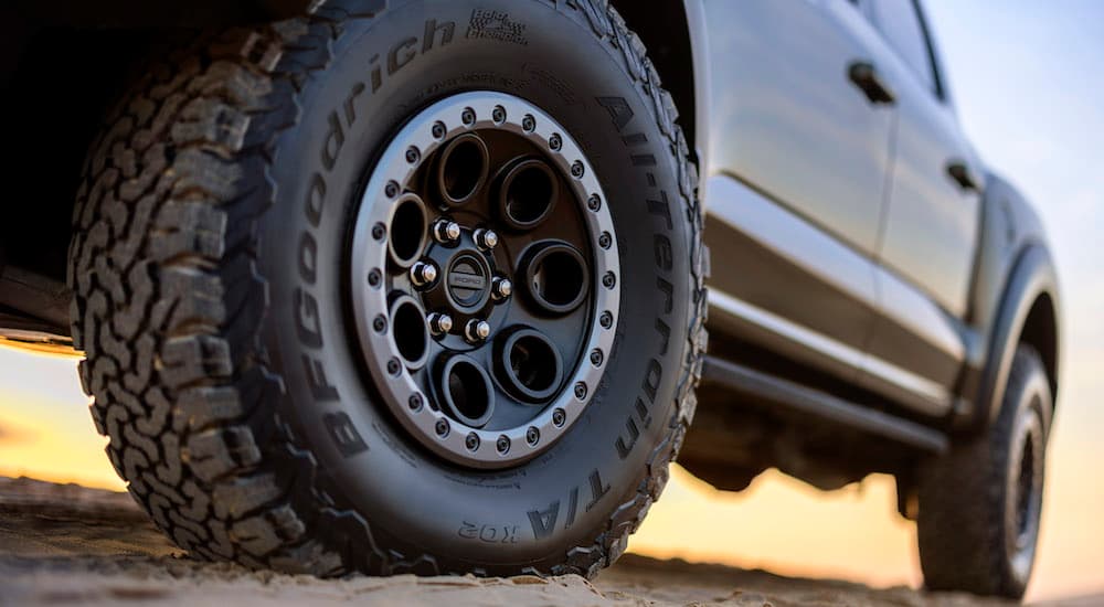 A close-up on the rear wheel of a green 2024 Ford F-150 Raptor is shown.