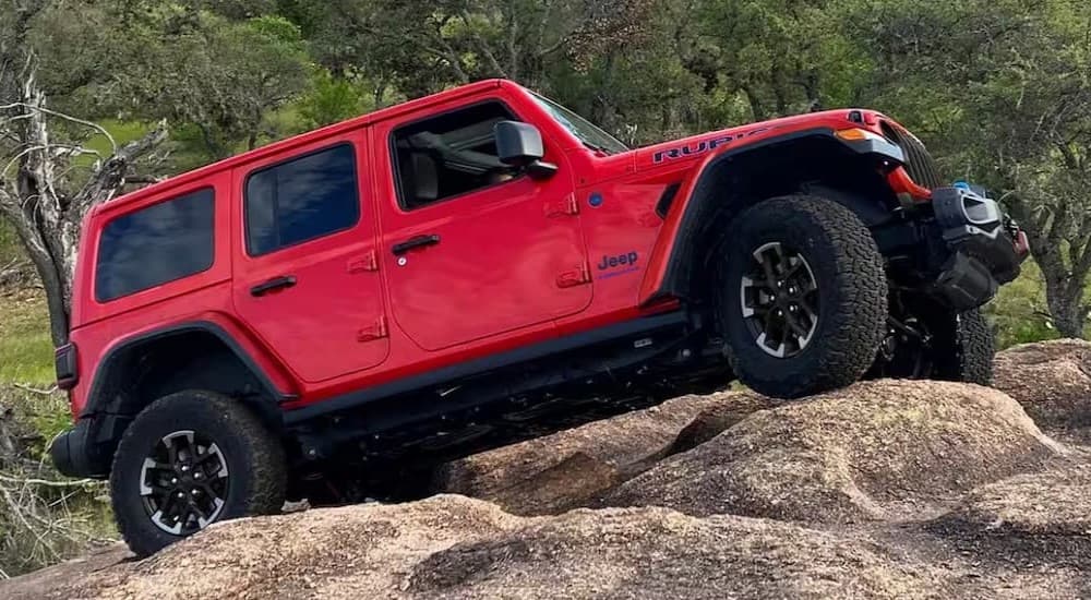 A red 2024 Jeep Wrangler Rubicon is shown driving off-road.