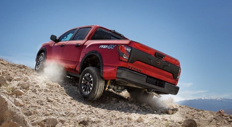A red 2024 Nissan Titan PRO-4X is shown driving off-road after visiting a Nissan Titan for sale.