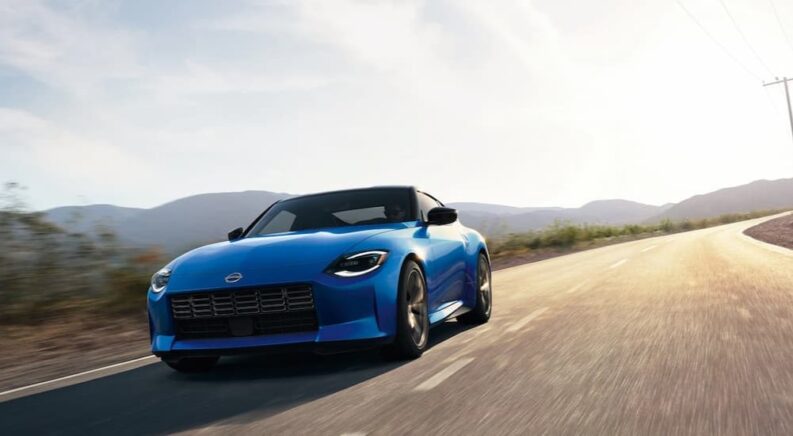 A blue 2024 Nissan Z is shown driving on a road after visiting a Nissan dealer.