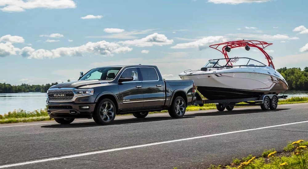 A black 2024 Ram 1500 is shown towing a boat after viewing a Ram 1500 for sale.