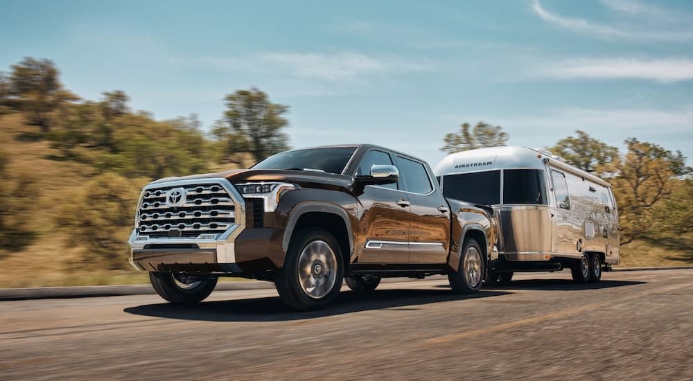 A brown 2024 Toyota Tundra 1794 Limited Edition is shown towing a trailer after viewing a Toyota Tundra for sale.