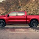 One of the newest Chevy trucks for sale, a red 2024 Chevy Silverado 1500 Z71, is shown parked near a lake.