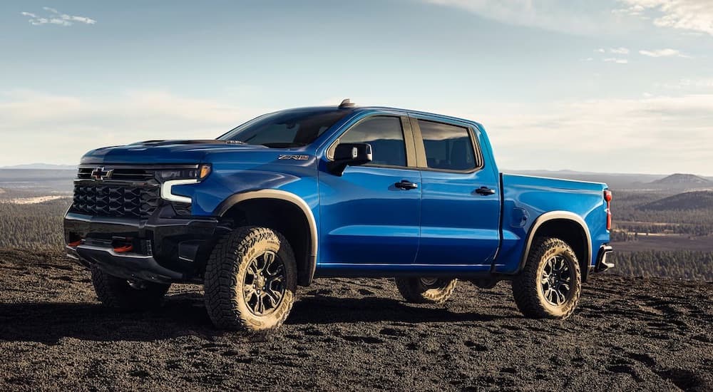A blue 2024 Chevy Silverado 1500 ZR2 is shown parked off-road in a desert.