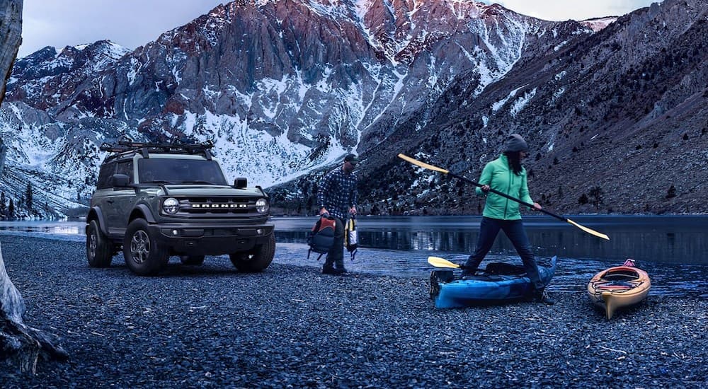 People are shown setting up camp near a grey 2021 Ford Bronco Big Bend parked beside a lake.