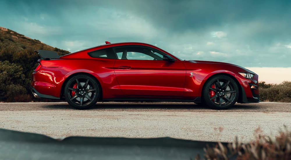 A red 2022 Ford Mustang Shelby GT500 is shown from the side on a cloudy day.