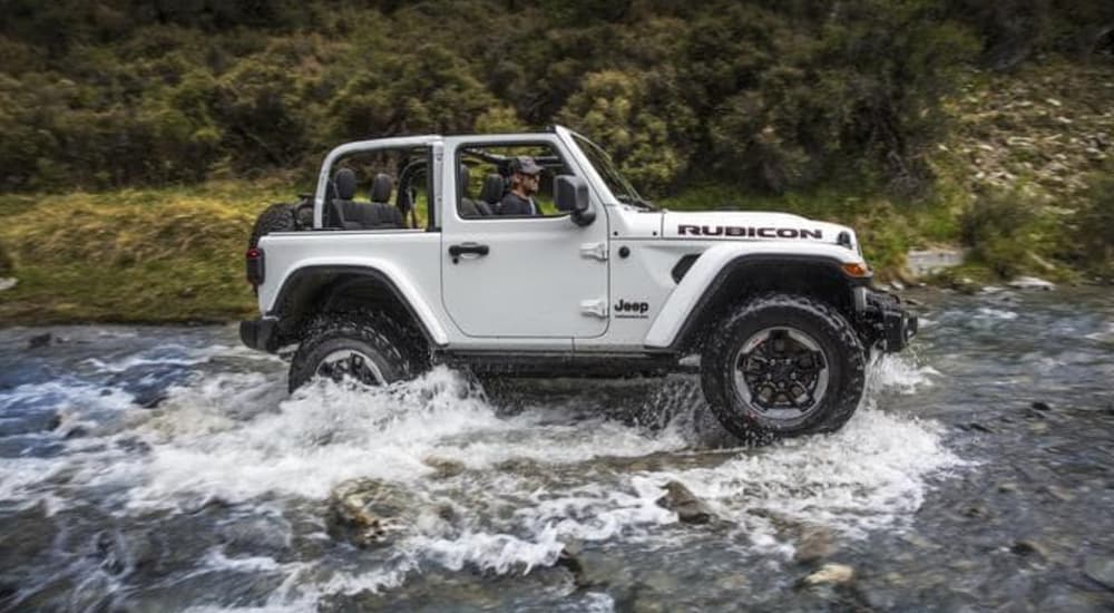 A white 2018 Jeep Wrangler Rubicon is shown driving over a river.