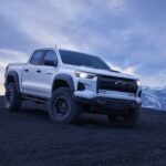 One of the most popular trucks for sale, a white 2024 Chevy Colorado ZR2 Bison, is shown driving off-road in a desert.