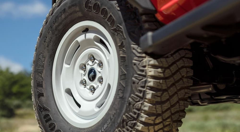 A close-up on the wheel of a red 2024 Ford Bronco Heritage is shown.