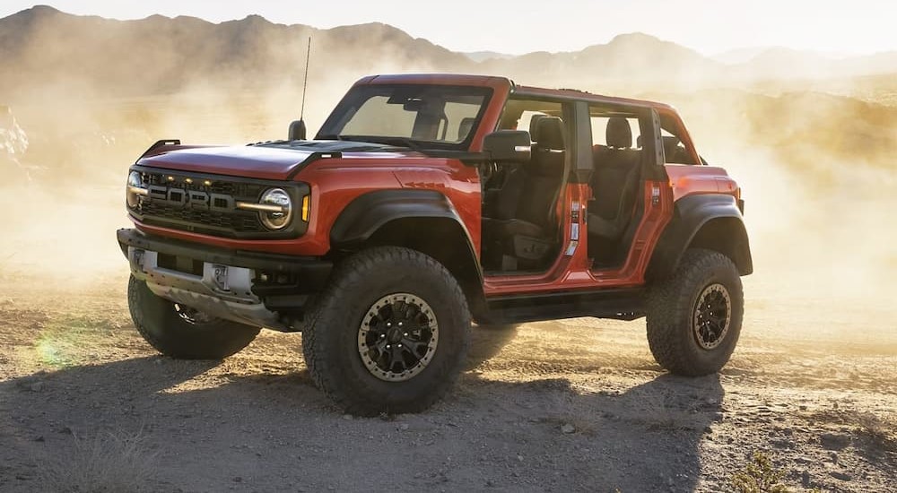 A red 2024 Ford Bronco Raptor is shown parked on dirt after visiting a Ford dealer.