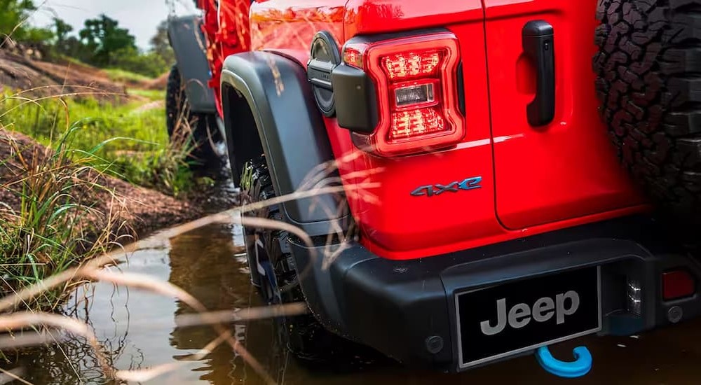 A red 2024 Jeep Wrangler 4xe is shown driving off-road after viewing a Jeep Wrangler for sale.