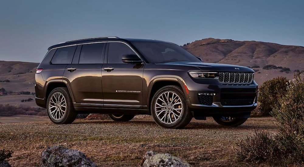 A black 2023 Jeep Grand Cherokee parked in the desert with mountains in the background.