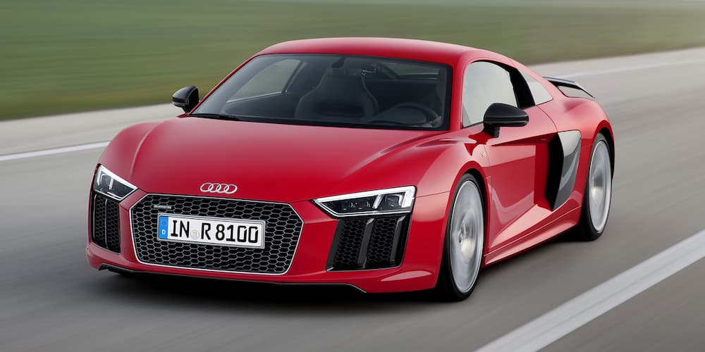 A red 2016 Audi R8 driving on a racetrack.