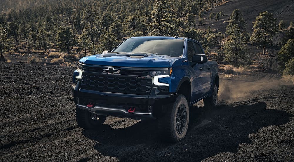 A blue 2024 Chevy Silverado 1500 ZR2 kicking up dust while off-roading.