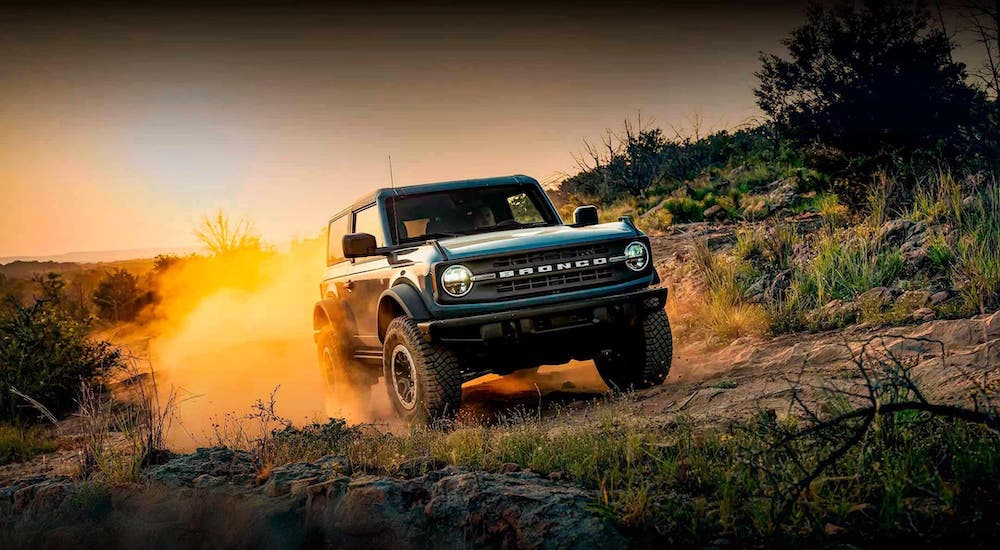 A blue 2024 Ford Bronco Sport is shown driving over a dusty trail.