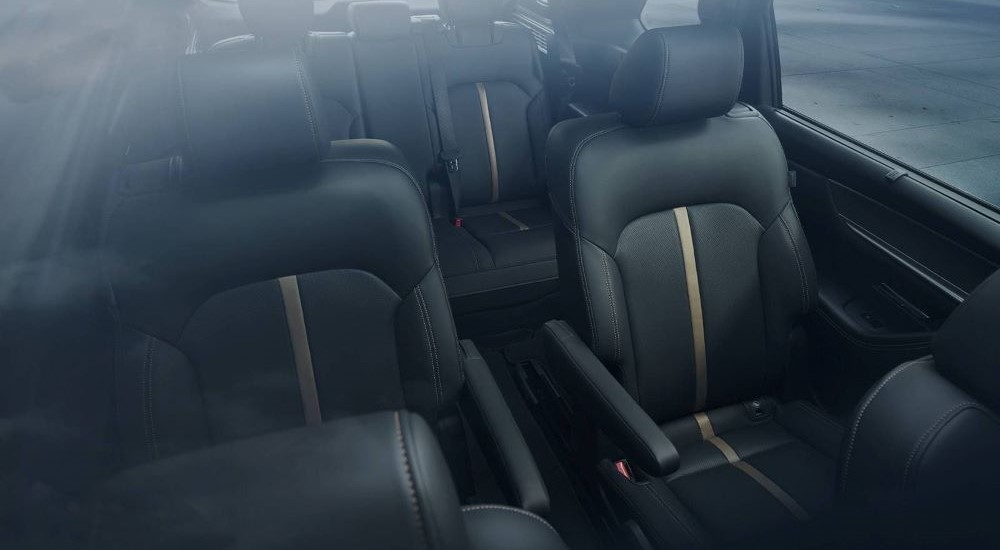 The second and third rows of seats in the black interior of a 2024 Mazda CX-90.