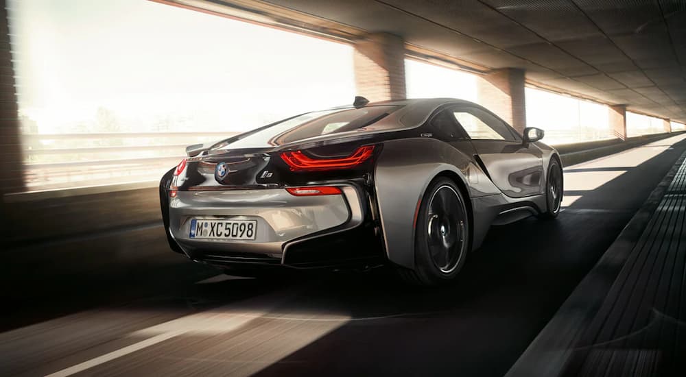 Rear view of a silver 2019 BMW i8 coupe driving on a bridge.