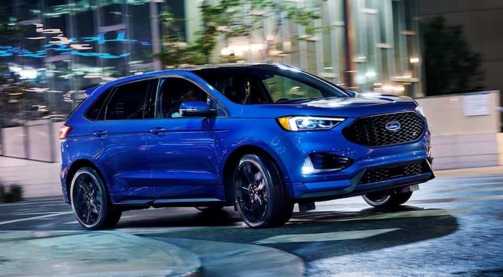A blue 2020 Ford Edge ST is shown driving to a Ford dealer. 