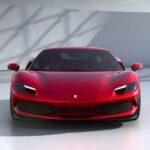 A red 2023 Ferrari 296 GBT is shown parked in a white room.