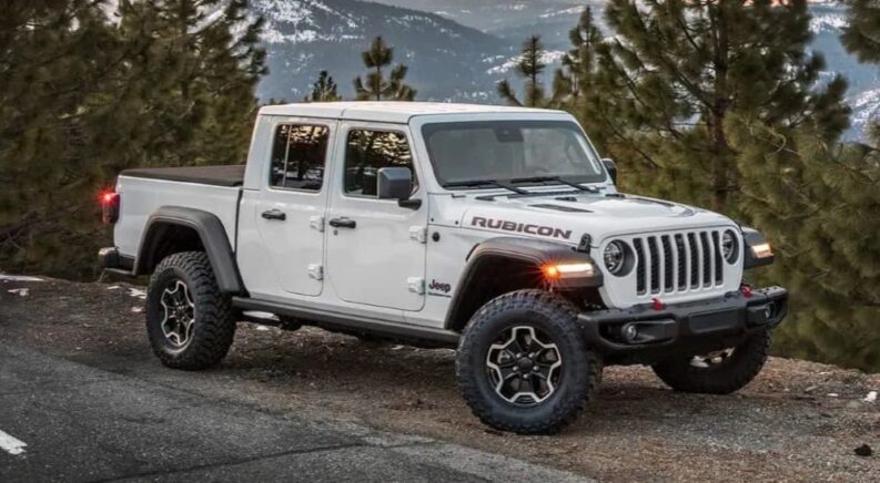 A white 2023 Jeep Gladiator Rubicon is shown parked off-road after visiting a Jeep dealer.