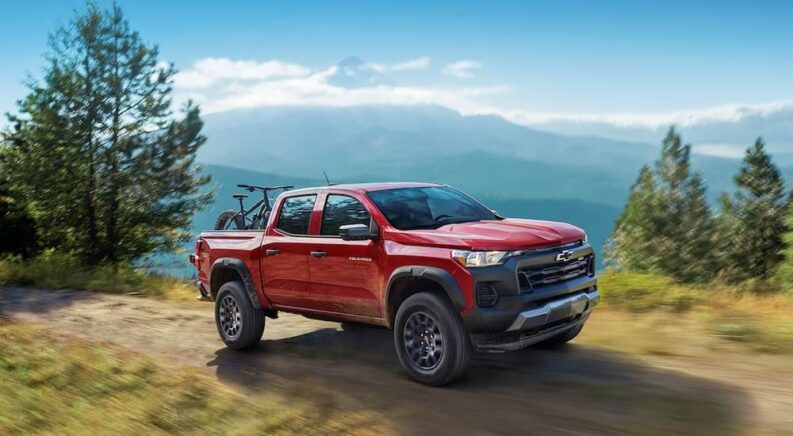 A red 2024 Chevy Colorado is shown driving on a dirt path.