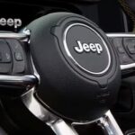 A close-up on the steering wheel in a 2024 Jeep Wrangler is shown at a Jeep dealer.