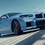 A blue 2024 BMW M2 Coupe is shown driving from a BMW M certified dealer.