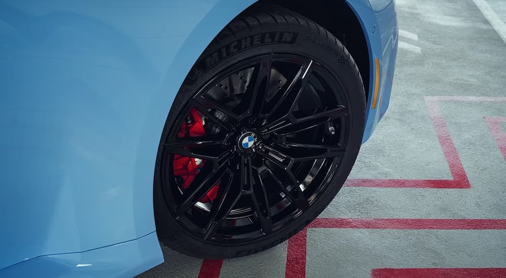 A close-up on the front wheel of a blue 2024 BMW M2 Coupe.