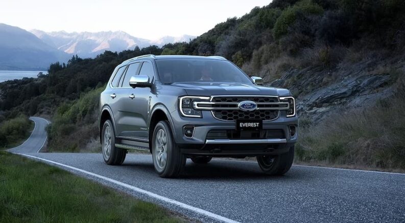 A grey 2024 Ford Everest is shown driving from a Ford dealer.