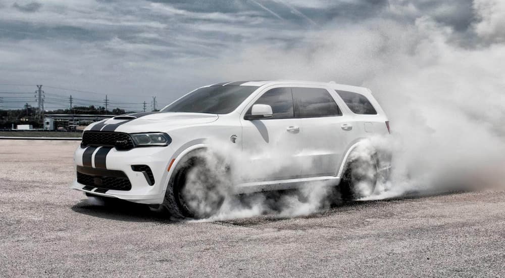 A white 2021 Dodge Durango SRT Hellcat is shown from the side while performing a burnout.