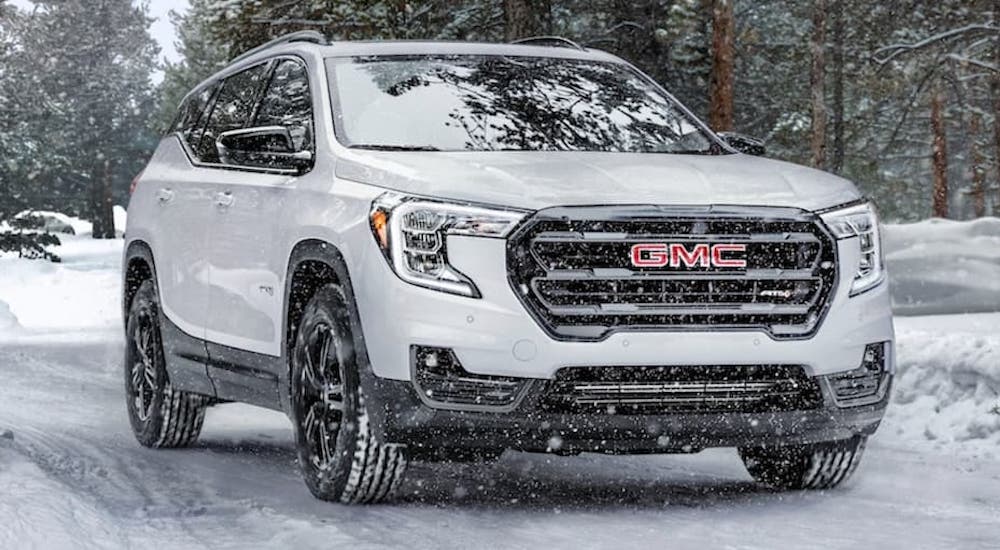 A white 2021 GMC Terrain AT4 is shown from the front at an angle in snow.