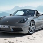 A gray 2024 Porsche 718 Boxster is shown parked near a mountain.